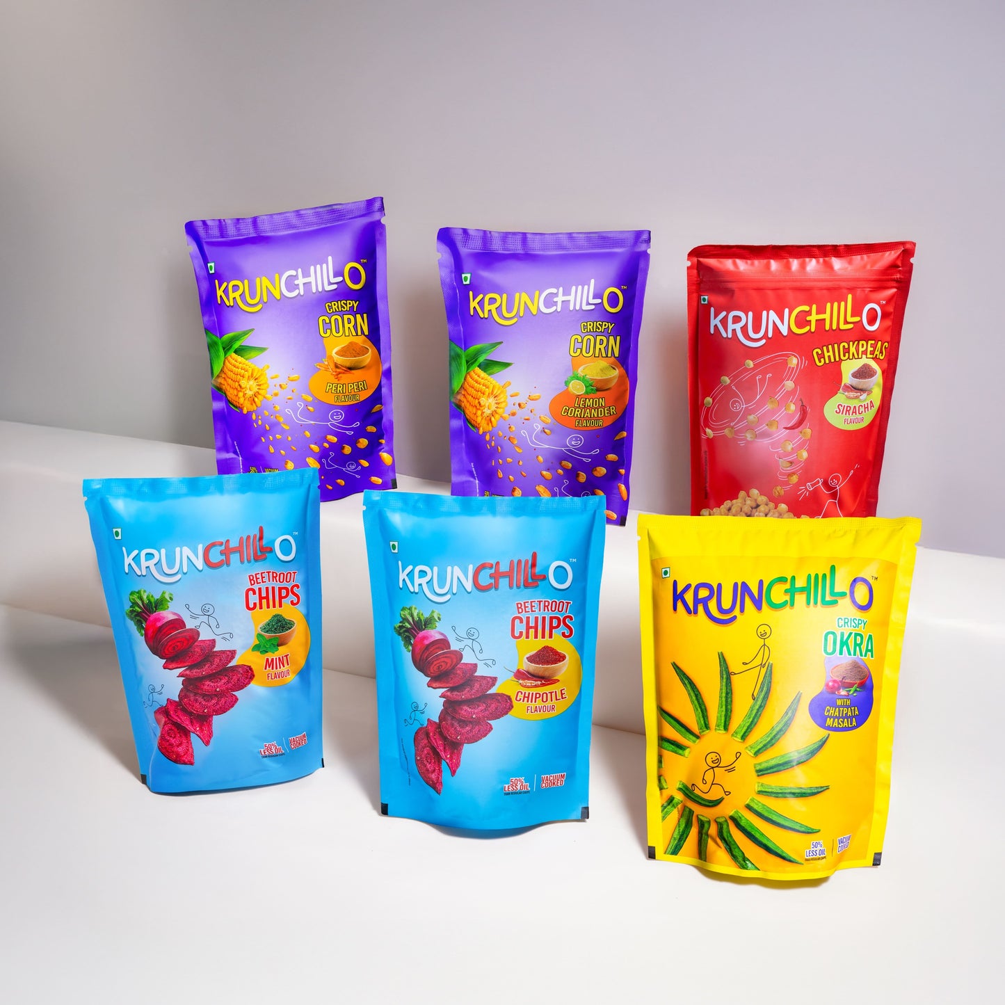 Colorful packages of Krunchillo snacks on a white surface with a gray background